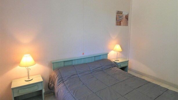 A bedroom with a bed, two bedside tables with lamps, a light switch, and a small picture on the wall. - Villa Bel Air - Leon (LEON)