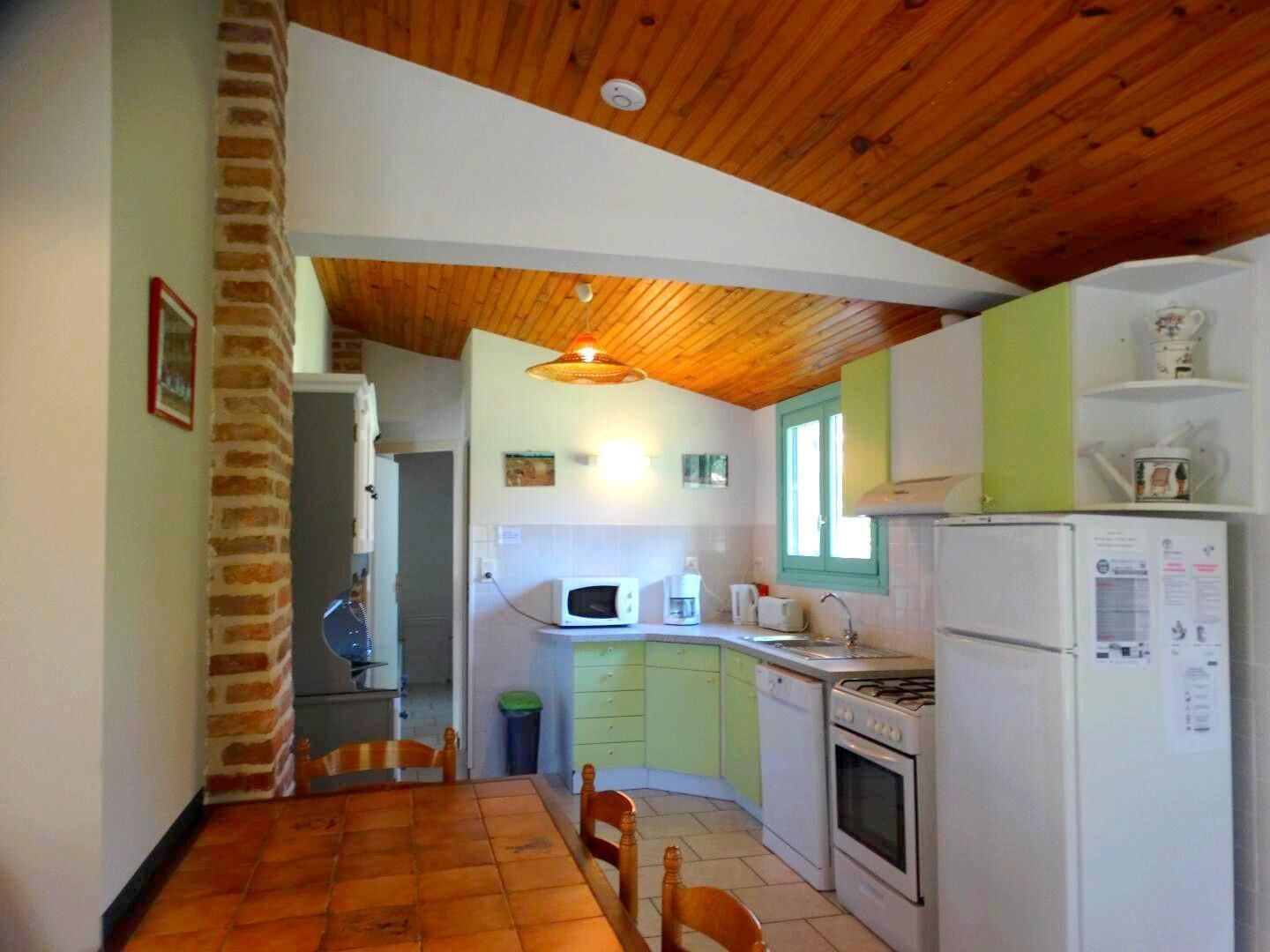 Una cocina funcional con techo de madera, una mesa de comedor y electrodomésticos básicos.