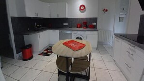 A compact kitchen with white cabinets, a black countertop, and a red clock on the wall. - Erable - Ste-eulalie-en-born (STE-EULALIE-EN-BORN)
