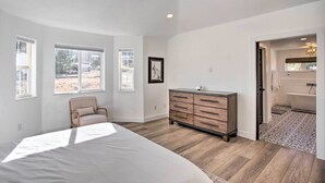 A bedroom with a bed, dresser, chair, and large windows. - Grand Junction Mountain Escape w/ Grill! (Grand Junction)