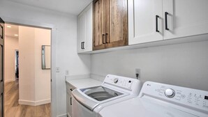 A laundry room with two white washing machines, wooden cabinets above, and a white countertop. - Grand Junction Mountain Escape w/ Grill! (Grand Junction)