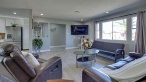 A modern living room with a brown leather sofa, a glass coffee table, and a flat-screen TV mounted on the wall. - Las Vegas Retreat w/ Yard < 5 Mi to Strip! (Las Vegas)
