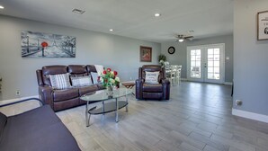 A spacious living room with a brown leather sofa, a glass coffee table, and a brown leather armchair. There is a painting on the wall and a door leading to another room. - Las Vegas Retreat w/ Yard < 5 Mi to Strip! (Las Vegas)