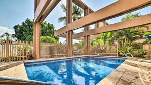 Una piscina con acqua cristallina, circondata da una recinzione in legno, con vista su palme e vegetazione sullo sfondo.