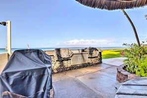 Eine Terrasse mit Grill, einer Steinsäule und Blick auf den Ozean.