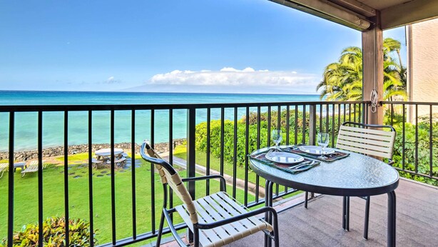 Un balcone con tavolo e sedie affacciato su una spiaggia.