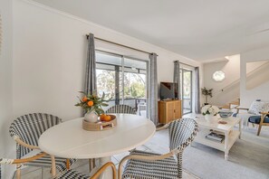 A modern living room with a round white table, patterned chairs, a television, and a view through large windows. - Lakefront Retreat w/ Kayaks & Fire Pit in Clermont (Clermont)