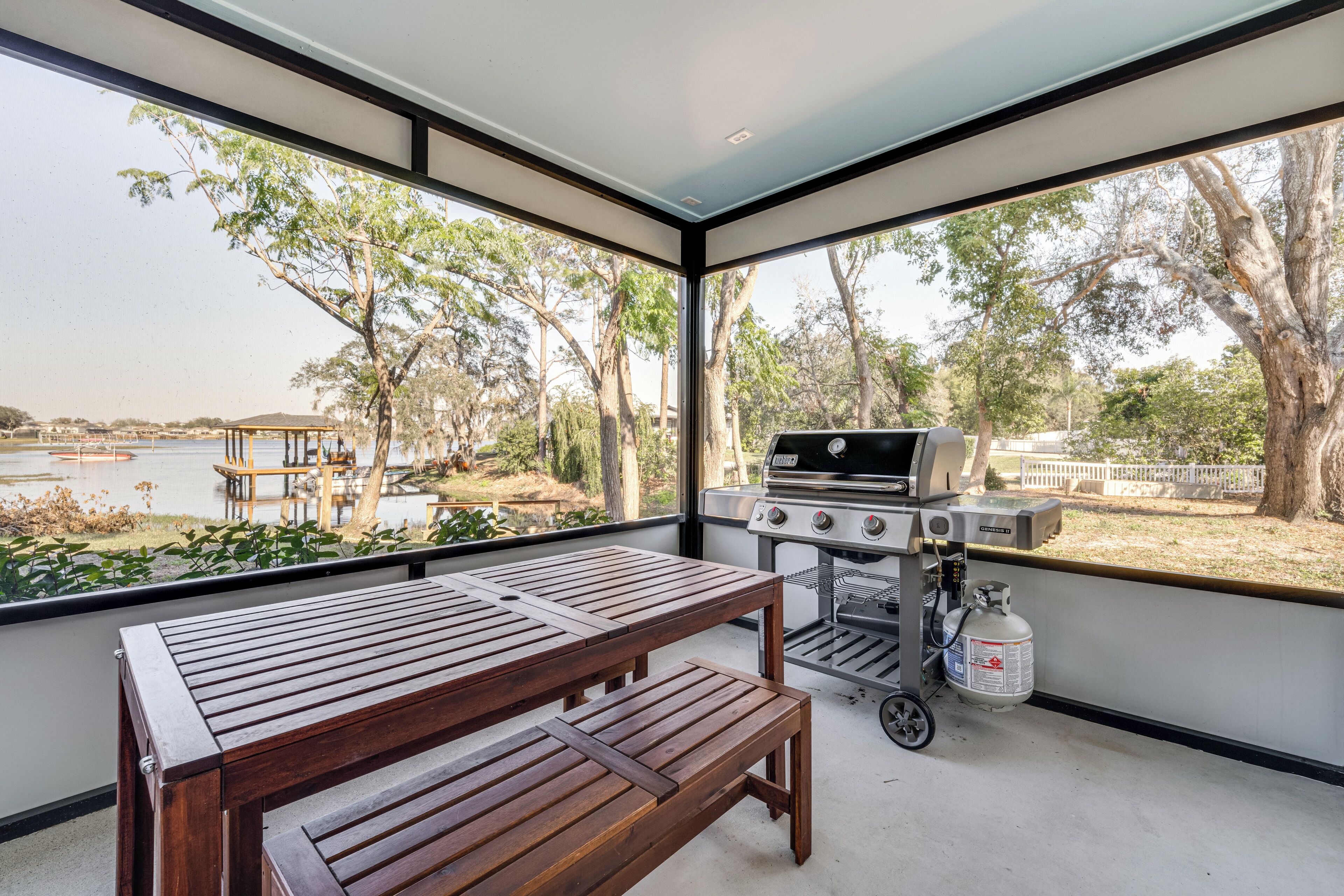 A balcony with a wooden table and bench, overlooking a lake and trees.