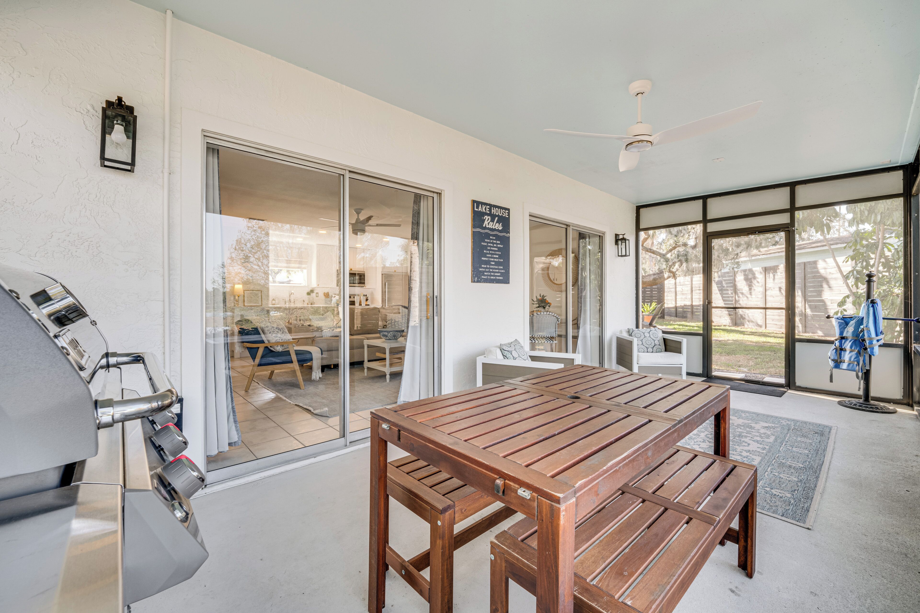Un patio con mesa y bancos de madera, una parrilla y un letrero que dice 'Lake House Rentals'.