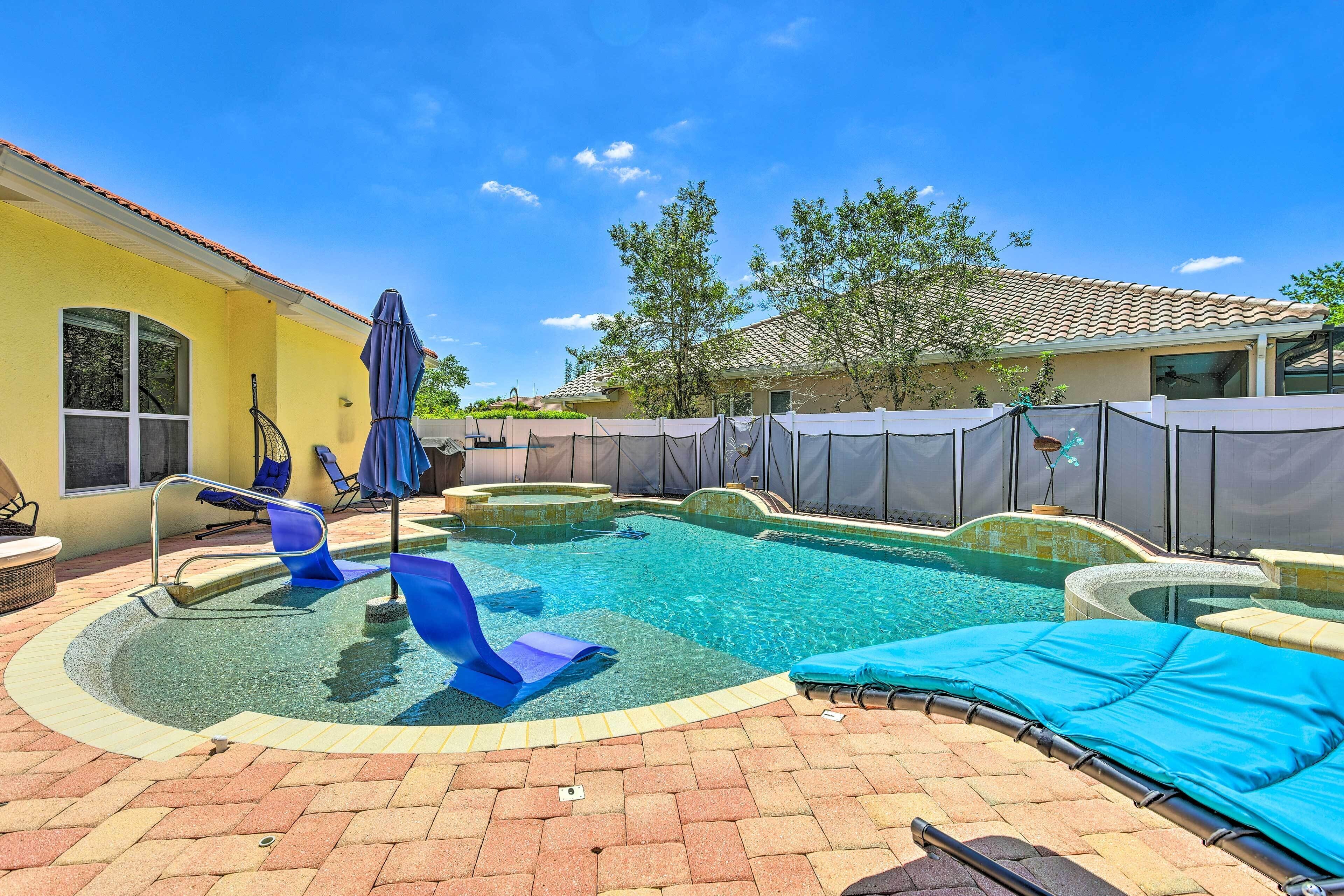 A backyard with a swimming pool, lounge chairs, and a covered patio area.