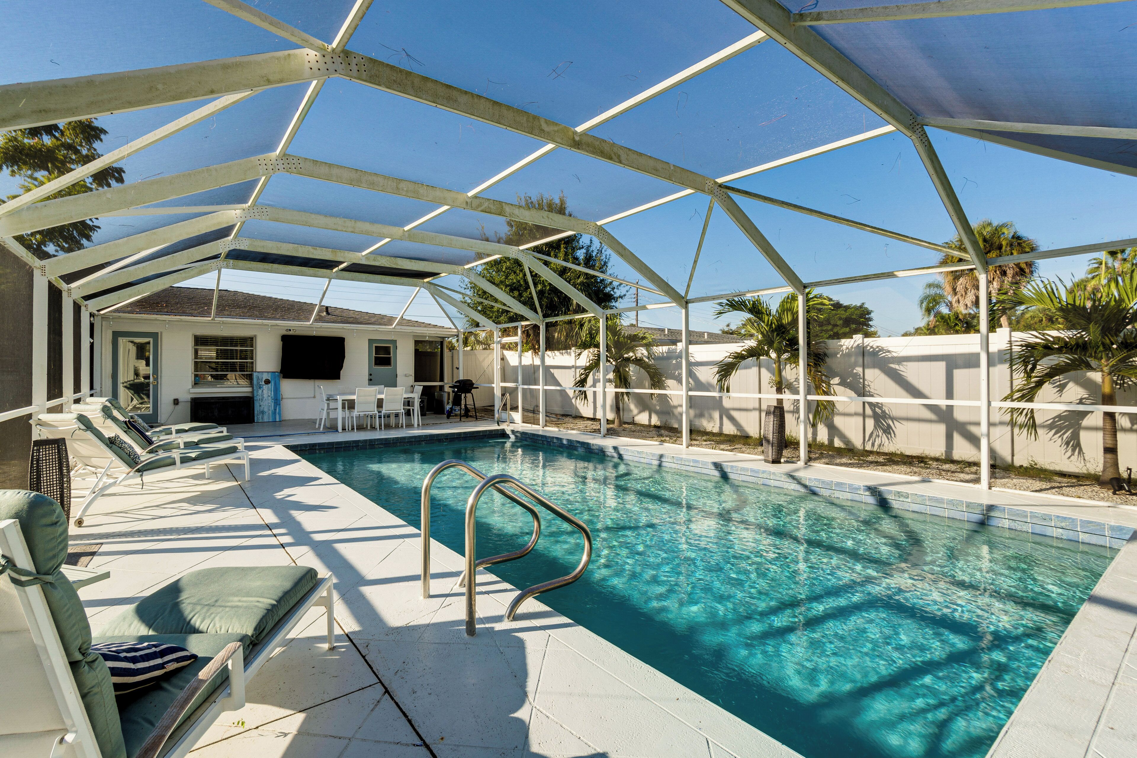 A covered swimming pool with lounge chairs and a patio area.