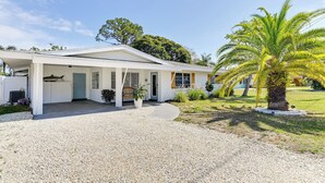 Une maison de plain-pied avec un porche couvert, une allée en gravier et un palmier dans le jardin.
