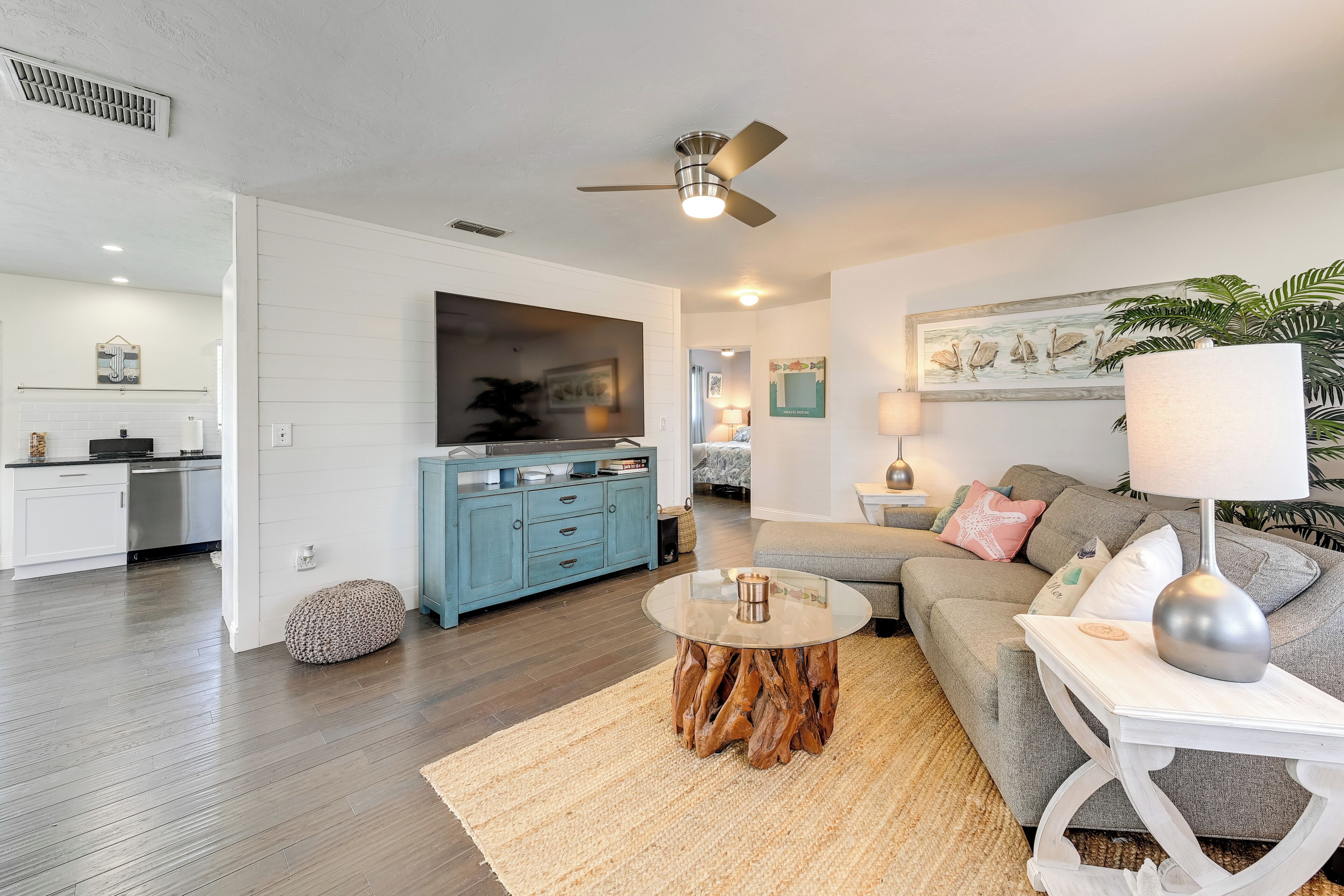A modern living room with a grey sofa, a round coffee table, and a ceiling fan.