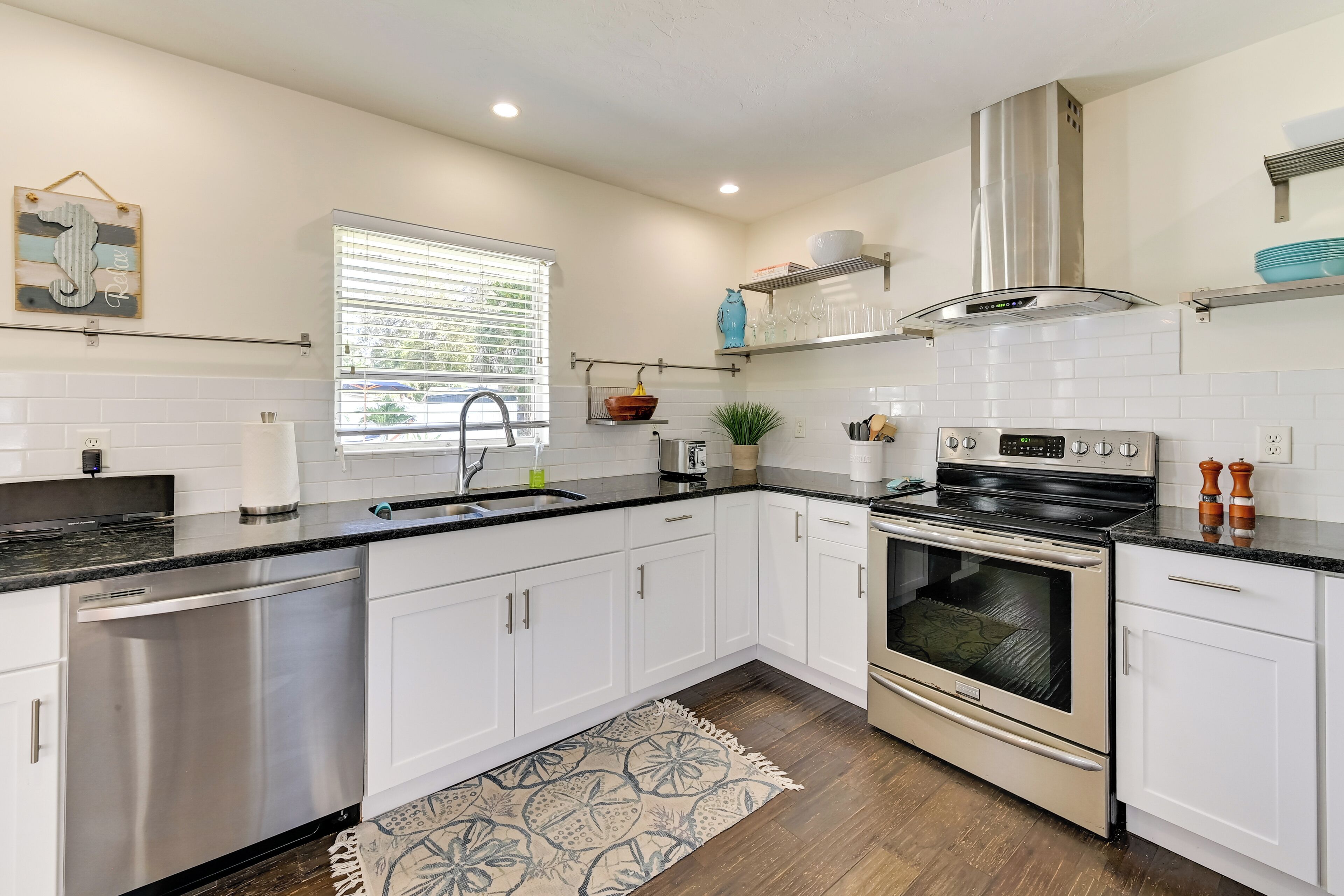 A modern kitchen with white cabinets, stainless steel appliances, and a black countertop.