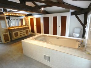 A spacious bathroom with a large bathtub, a vanity with a sink, and a toilet.