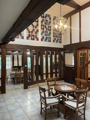 A dining area with wooden furniture and a large window with colorful stained glass.