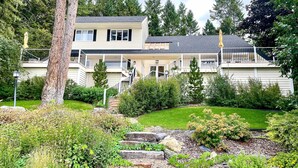 A two-story house with a balcony, surrounded by a well-maintained garden and trees. - Peaceful Lakeside Retreat w/ Deck & Amazing Views! (Lakeside)