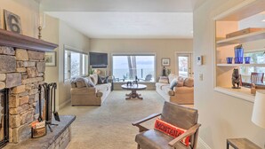 A cozy living room with a stone fireplace, two sofas, a coffee table, and a view of the outdoors. - Peaceful Lakeside Retreat w/ Deck & Amazing Views! (Lakeside)