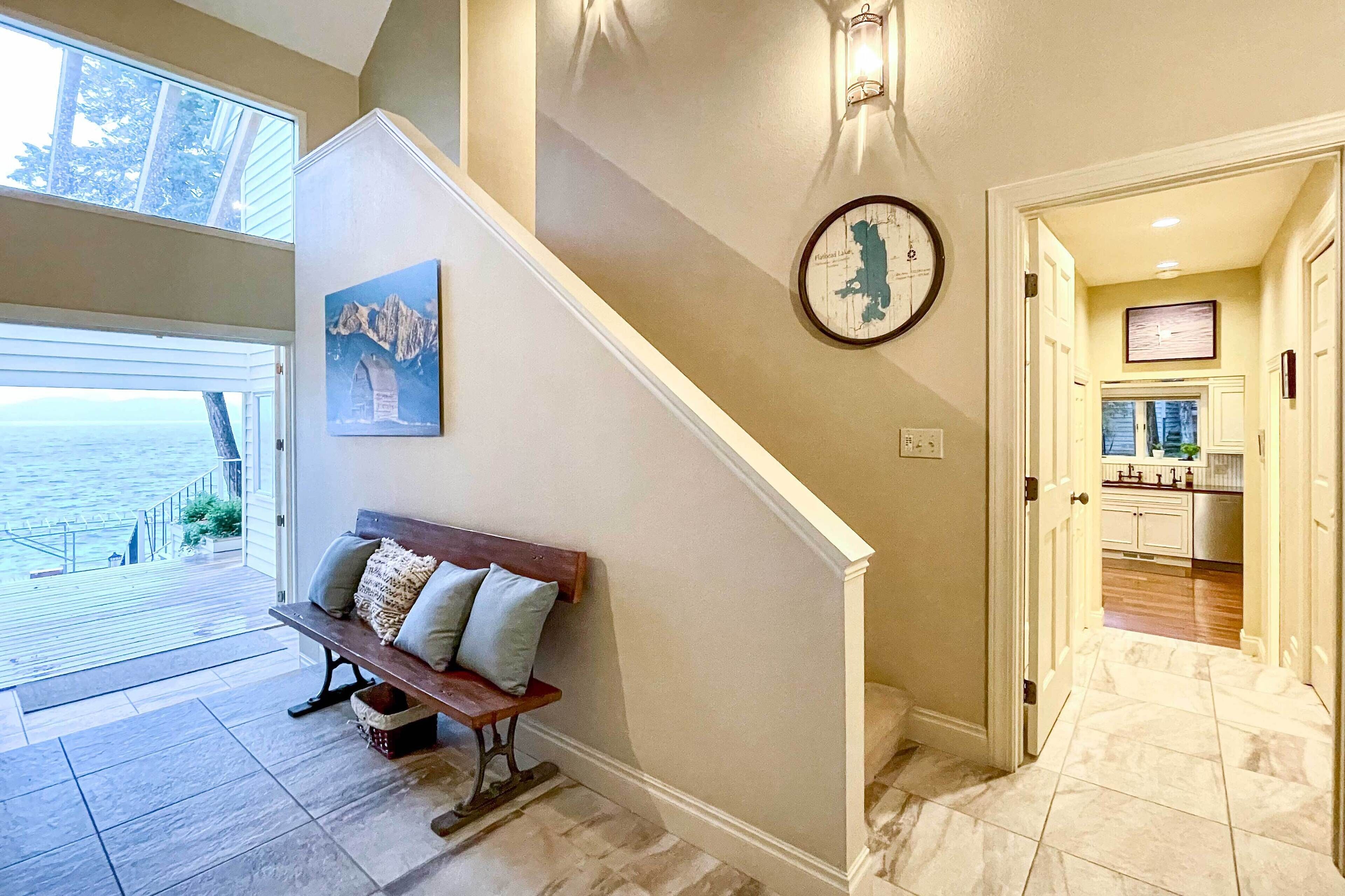 A staircase with a bench, a wall clock, and a framed map.