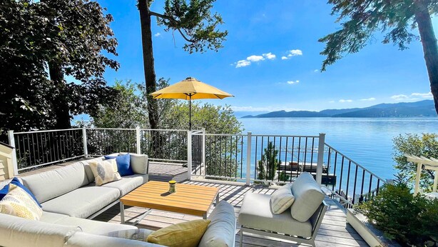 A deck with a sofa, chairs, and a table, overlooking a lake with mountains in the distance. - Peaceful Lakeside Retreat w/ Deck & Amazing Views! (Lakeside)