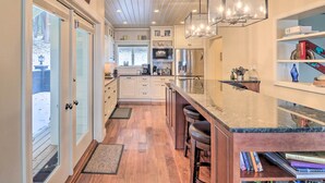 A modern kitchen with white cabinetry, a marble countertop, and a built-in island with bar stools. - Peaceful Lakeside Retreat w/ Deck & Amazing Views! (Lakeside)