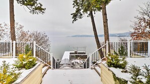 A staircase leading to a dock by a lake, surrounded by snow-covered plants and trees. - Peaceful Lakeside Retreat w/ Deck & Amazing Views! (Lakeside)