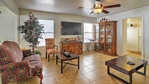 A living room with a sofa, a coffee table, a cabinet, and a ceiling fan. - Spacious Las Vegas Home - Near Golfing & Hiking! (Las Vegas)