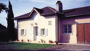 Ein zweistöckiges Haus mit einer symmetrischen Fassade, einem zentralen Eingang mit Tür und Fenstern sowie einem Schornstein.