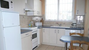 Eine Küche mit weißen Schränken, einer Mikrowelle, einem Toaster, einem Spülbecken und einem Holzespeisetisch mit Stühlen.