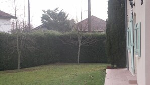 Ein Wohngrundstück mit gepflastertem Weg, Rasen und Hecke.