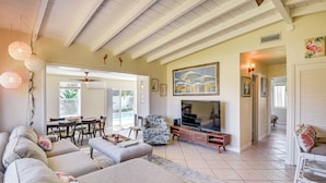 A spacious living room with a large TV, comfortable seating, and a dining area. - Ormond Beach Retreat: Walk to Shore & Shops! (Ormond Beach)