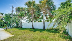 A well-maintained yard with palm trees, a white fence, and a concrete path. - Ormond Beach Retreat: Walk to Shore & Shops! (Ormond Beach)