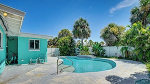A turquoise house with a swimming pool, surrounded by palm trees and a white fence. - Ormond Beach Retreat: Walk to Shore & Shops! (Ormond Beach)