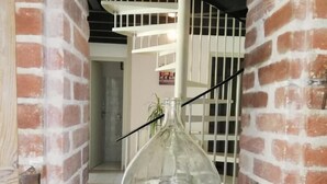 A glass vase hanging in a brick-walled alcove with a staircase in the background. - Arsuzon - Josse - Gîte (JOSSE)