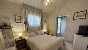 A bedroom with a bed, bedside tables, a lamp, a chair, a desk, and a television.