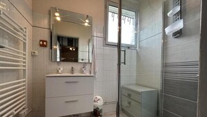 A modern bathroom with a glass shower enclosure, a large mirror, and a vanity with a sink.