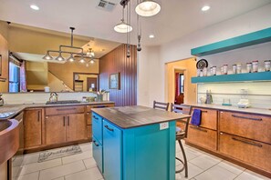 A modern kitchen with wooden cabinets, a blue island, and pendant lighting. - Pet-friendly OKC Home w/ Yard ~ 5 Mi to Dtwn! (Oklahoma City)