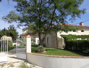 Una casa con fachada blanca, techo de tejas rojas y entrada protegida por una reja.