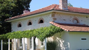A white building with a red-tiled roof, arched windows, and a covered porch with potted plants. - Lajenet - Benquet - Gîte (BENQUET)