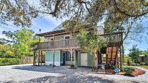 A two-story house with a covered porch, a front door, and a small garden area with decorative plants. - Pensacola Home - 2 Blocks From Boat Launch! (Pensacola)