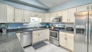 A modern kitchen with white cabinets, stainless steel appliances, a built-in microwave, and a water dispenser. - Pensacola Home - 2 Blocks From Boat Launch! (Pensacola)