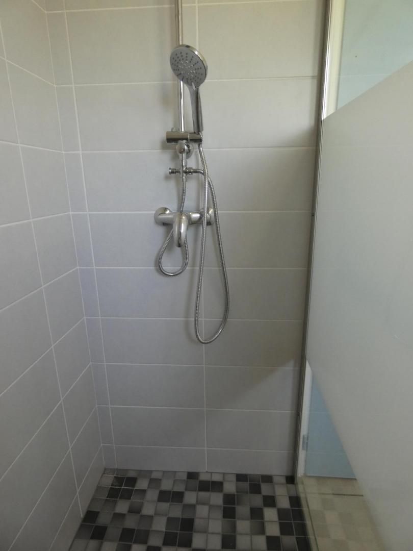 A shower with a handheld showerhead and a handheld hose.