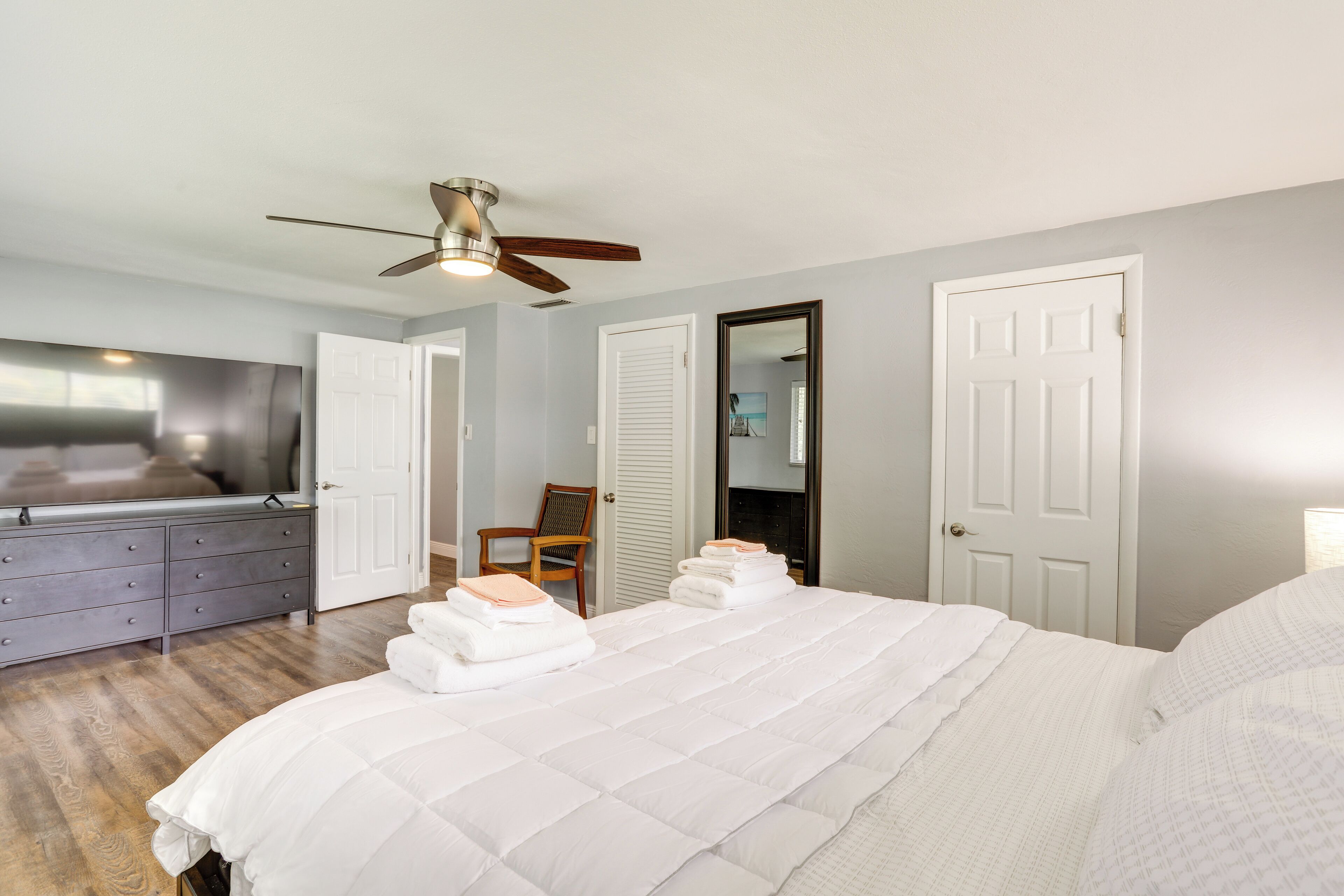 Une chambre à coucher avec un grand lit, un ventilateur de plafond, une commode et une chaise.