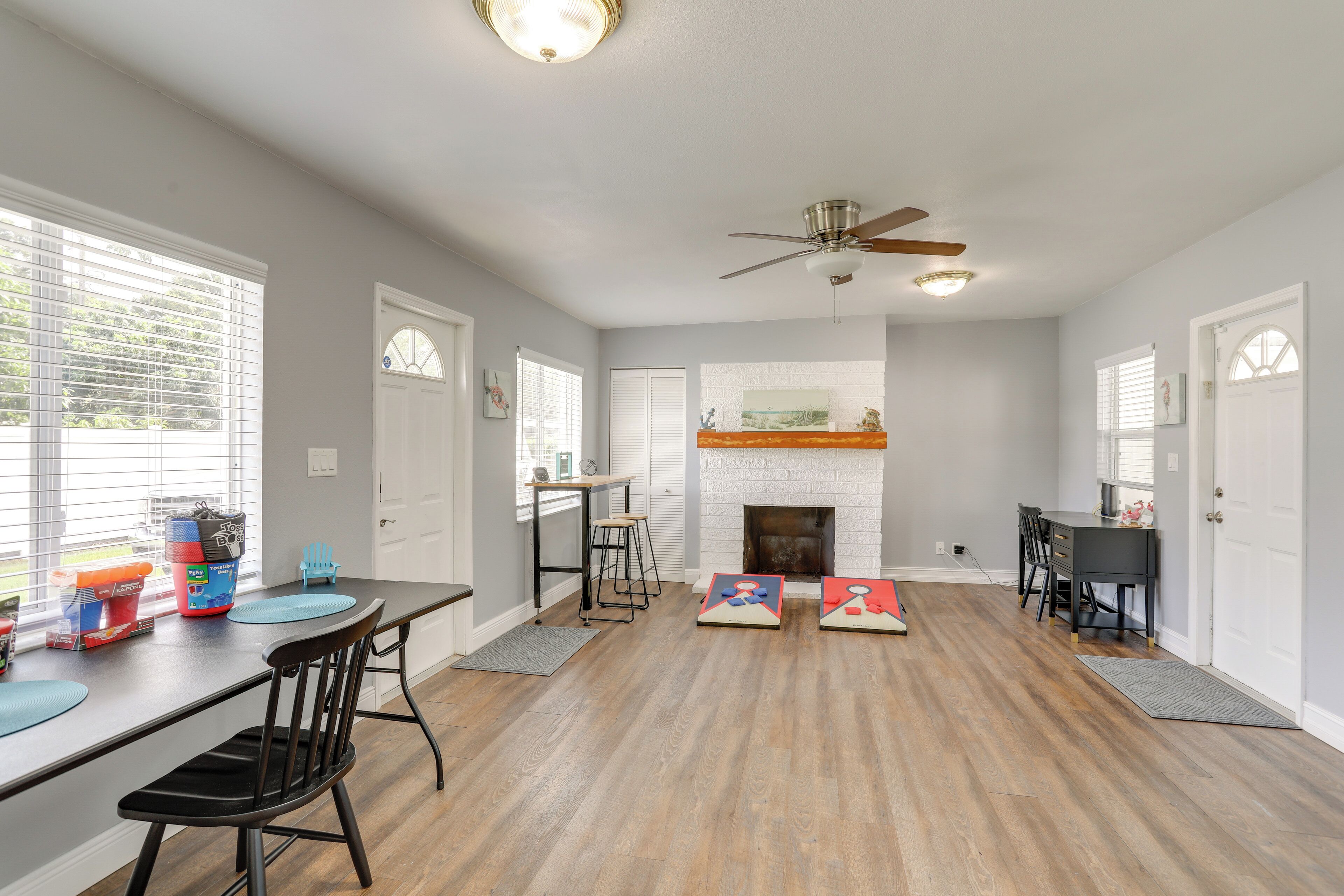 A spacious living room with a fireplace, a dining area with a table and chairs, and a ceiling fan.