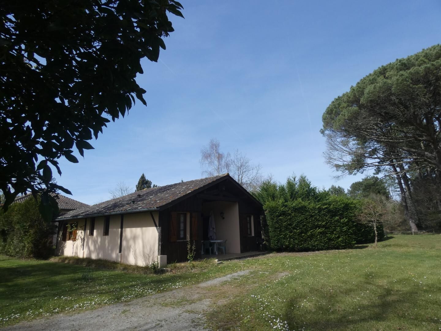 A rustic house with a sloped roof, a small porch, and a grassy yard.