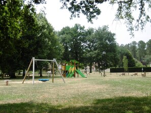 Children can play on the swing set, slide, and climbing structure in this park playground.