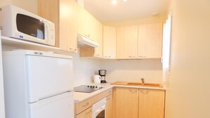 A compact kitchen with a refrigerator, microwave, stove, and sink. - Chez Michel 1 - Angoume (ANGOUME)