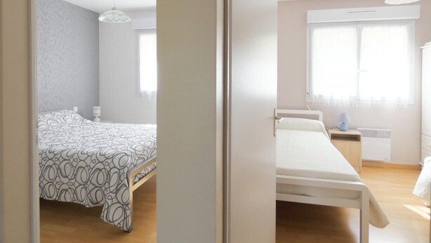 A bedroom with a bed, bedside table, lamp, and window. - Chez Michel 1 - Angoume (ANGOUME)