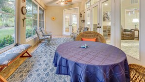 A sunroom with a large window, a ceiling fan, a round table with a tablecloth, and wicker furniture. - 4 Mi to WEC & 10 Mi to Hits, Golf Course Home (Ocala)