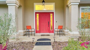A red door with two chairs outside, a small garden with plants, and a pathway leading to the door. - 4 Mi to WEC & 10 Mi to Hits, Golf Course Home (Ocala)